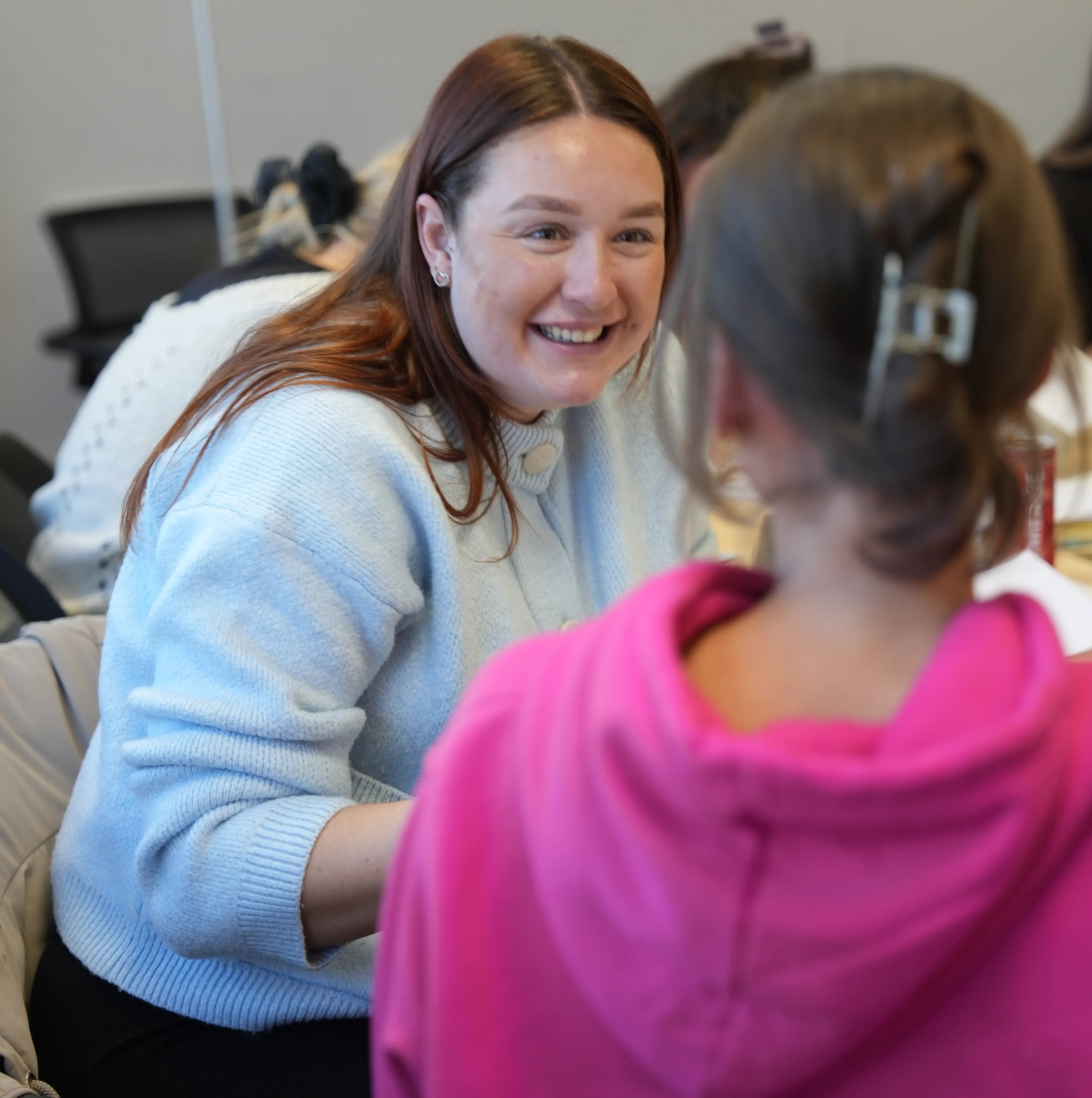 Woman smiling at child in pink hoodie.