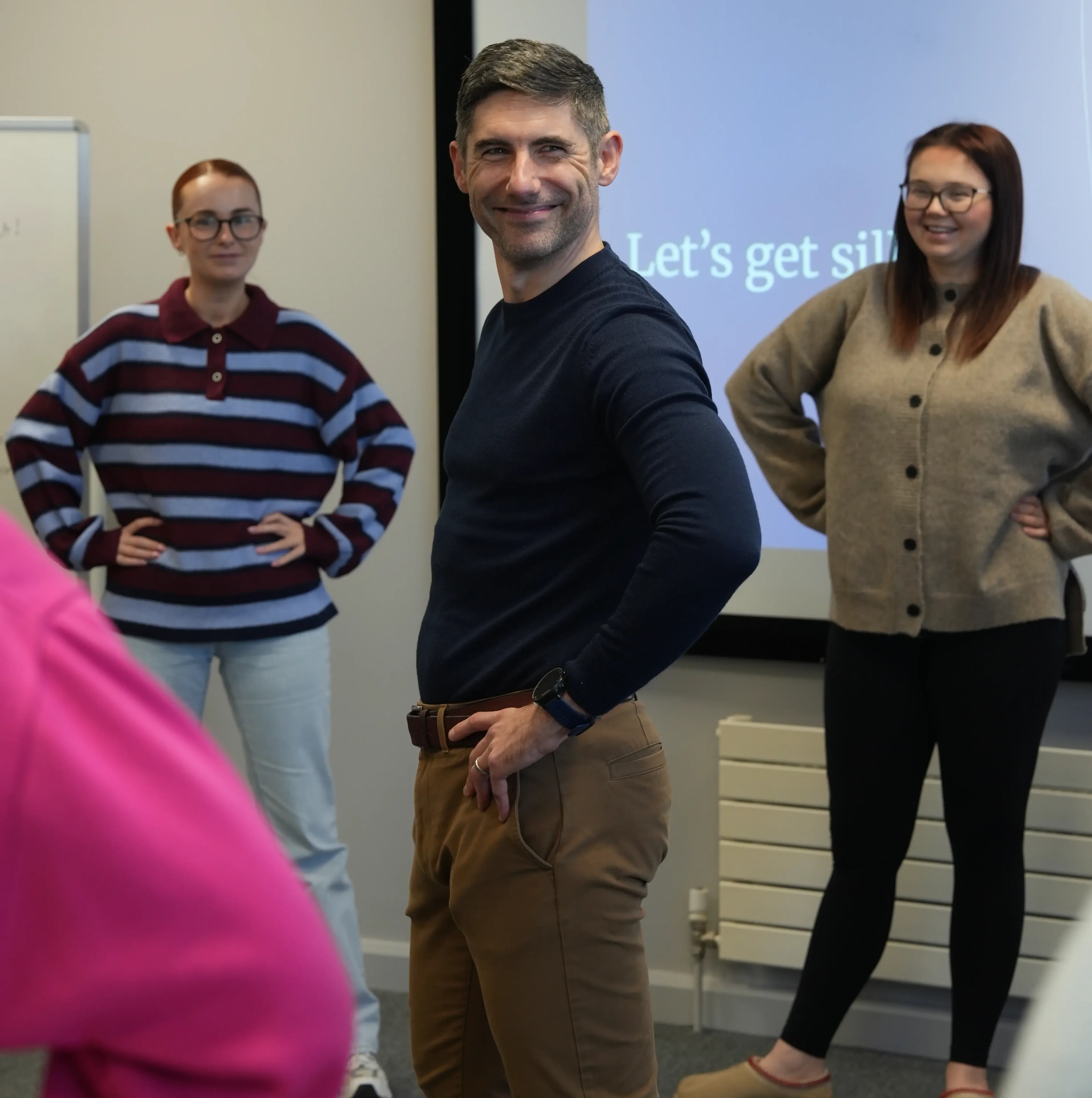 People posing with hands on hips, smiling.