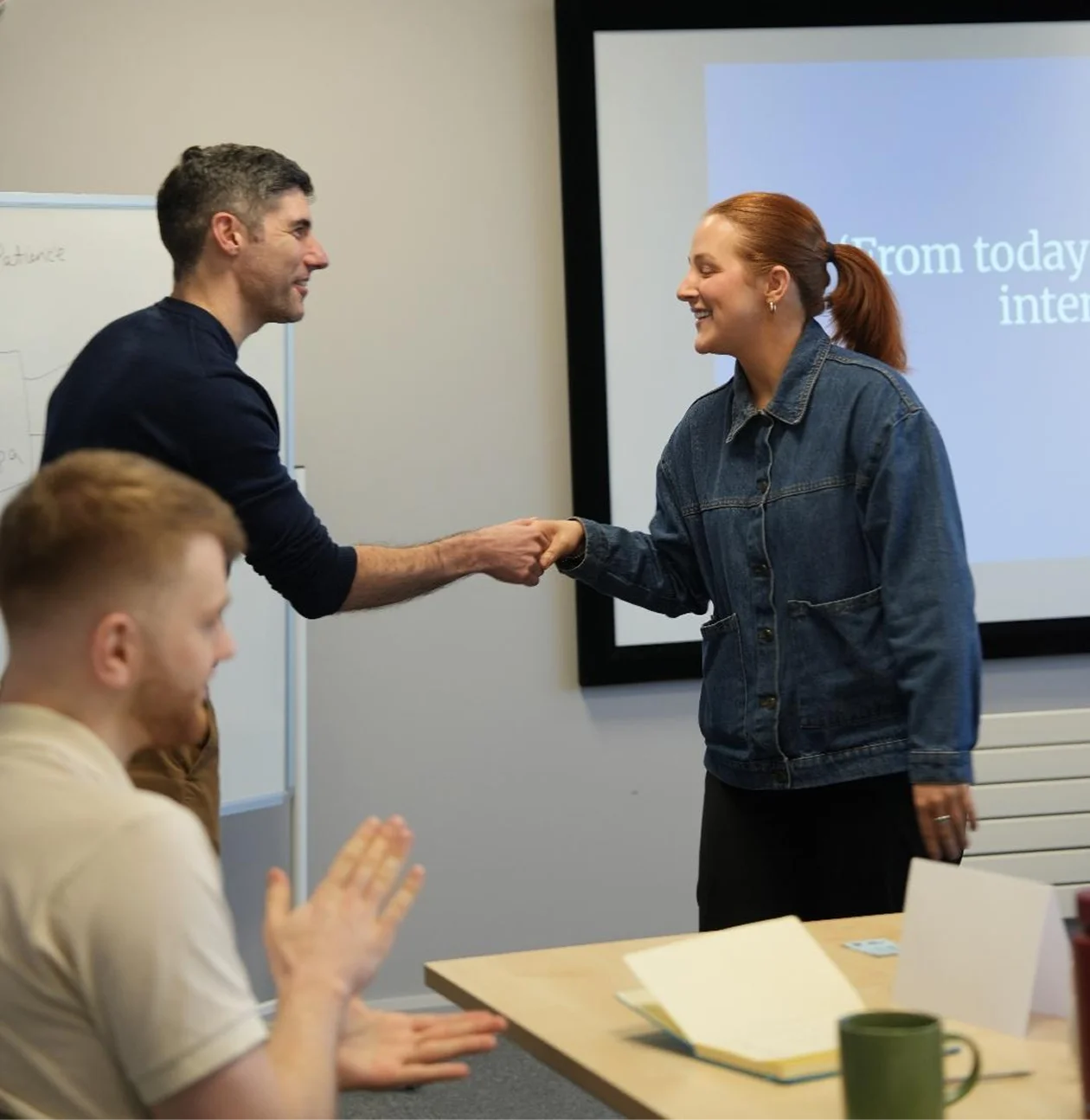 Two people shaking hands in meeting.